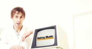 A man in a lab coat standing in front of an old computer.